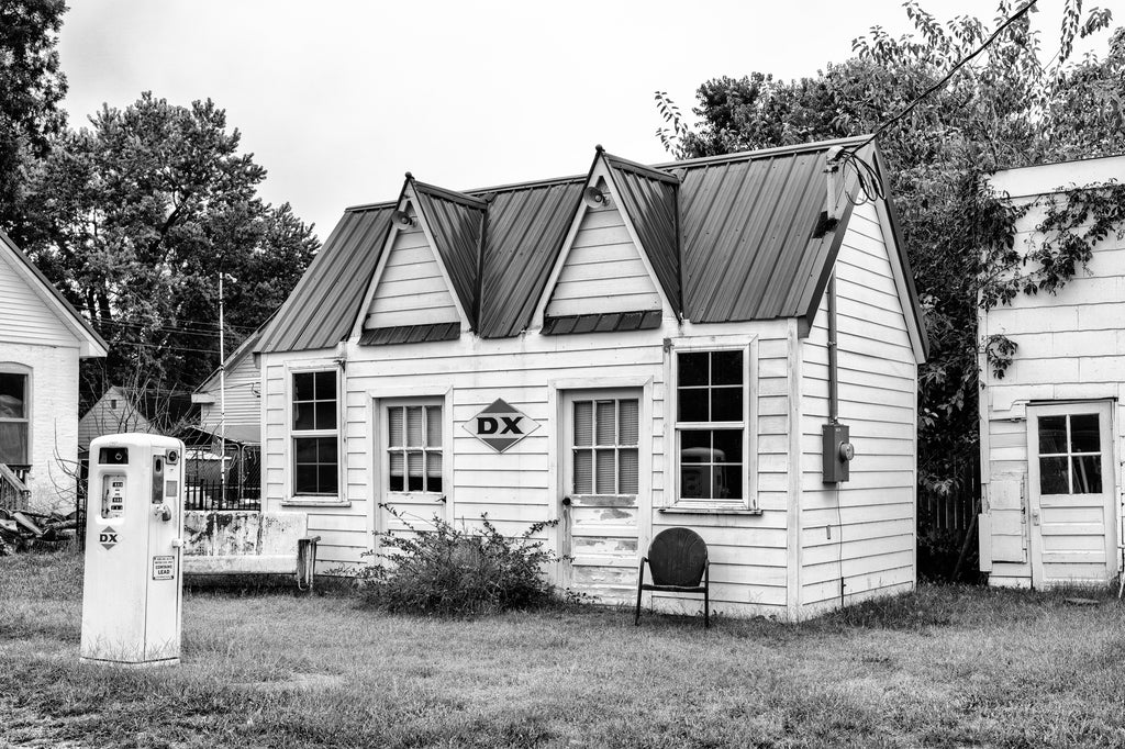 Black and white photograph of a long vacant vintage DX gasoline station on the side of the road in a small town in southern Illinois.