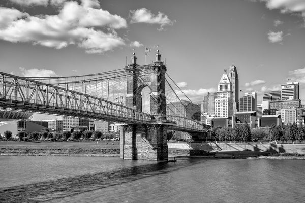 Black and white photograph of the John A. Roebling Suspension Bridge with the city of Cincinnati in the background. Built in 1866, the bridge was the longest suspension bridge in the world, but was later surpassed by Roebling's Brooklyn Bridge, built in 1883.