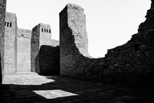 Black and white photograph of towering stone ruins of an abandoned old stone church in the American Southwest.