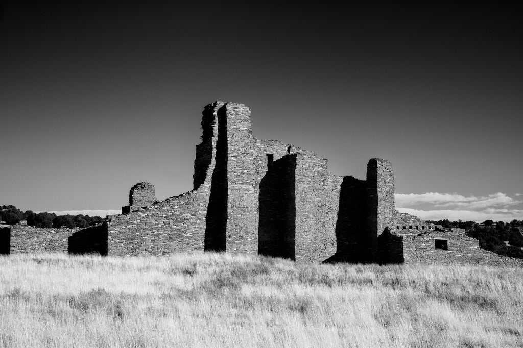 Black and white photograph of the massive stone ruins of the 1600s-era Abó Pueblo Mission in the desert of New Mexico.