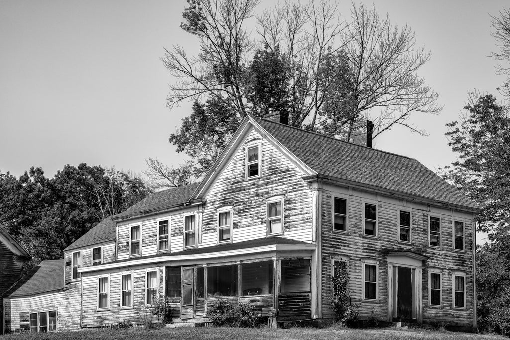 Black and white photograph of a huge 1868 farmhouse with an attached barn found along a rural highway in New Hampshire.