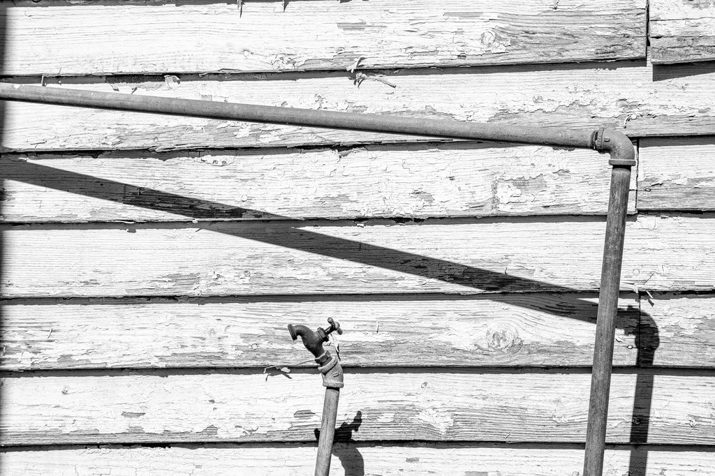 Black and white photograph of a water faucet outside the abandoned Trew General Merchandise Store built in 1903 in rural East Tennessee.