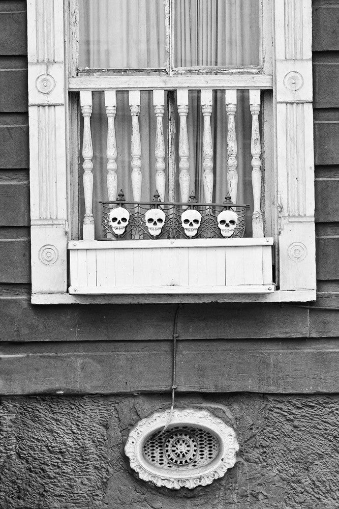 Black and white architectural detail photograph of a house in the New Orleans French Quarter, with little skulls on the window.