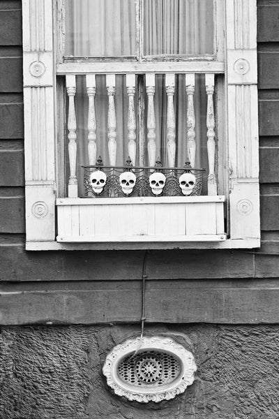 Black and white architectural detail photograph of a house in the New Orleans French Quarter, with little skulls on the window.