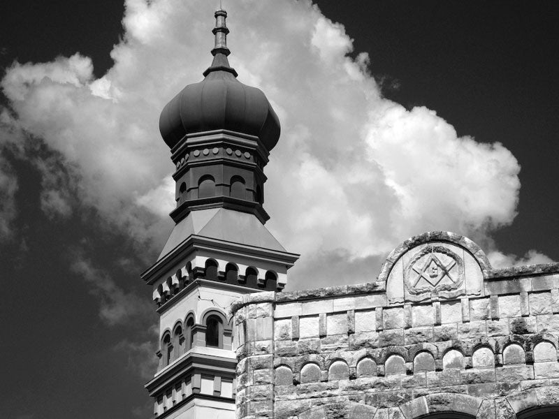 Black and white architectural photograph of a historic limestone building with a characteristic onion dome, sitting on a corner in the downtown courthouse square of Georgetown, Texas.