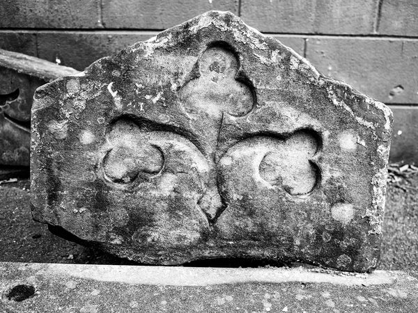 Black and White Photograph of a broken Carved Stone Architectural Fragment with Shamrock Design