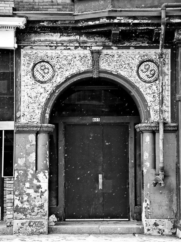Black and white architectural photograph of a shabby industrial building dated 1899, in an older section of Milwaukee.