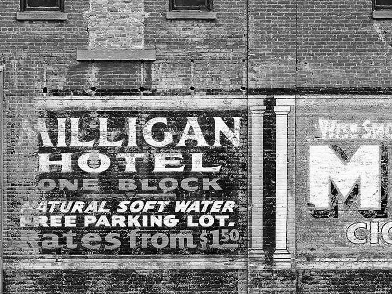 Black and white fine art photograph of a painted ad for the Milligan Hotel on a brick wall in Miles City Montana.