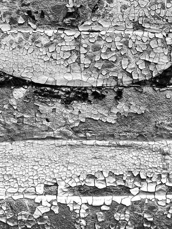 Black and white fine art photograph of a chips and flakes of paint on a brick wall in Miles City, Montana.