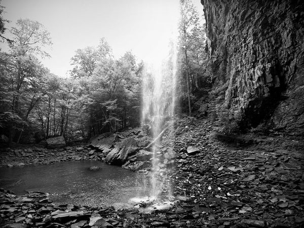 Black and white landscape photograph the tall waterfall dropping into a rocky pool at Ozone Falls, Tennessee.