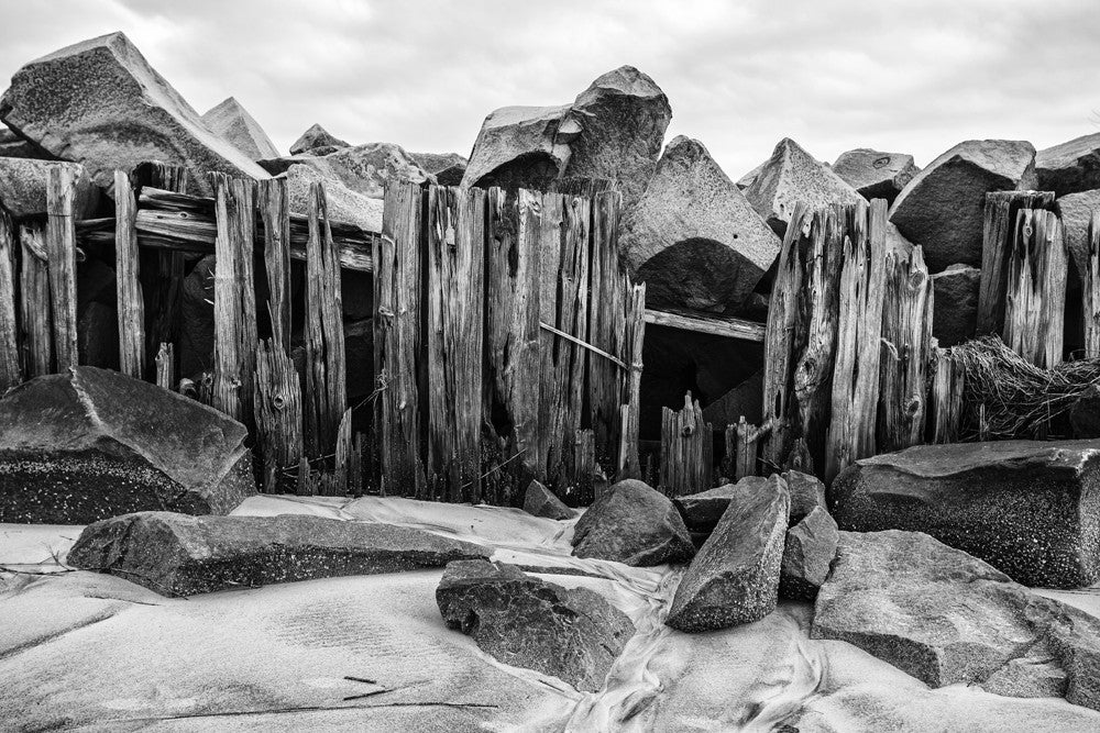 Black and white landscape photograph of a weathered beach fence on the bay at Charleston, South Carolina