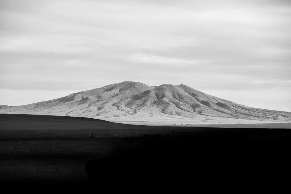 Black and white landscape photograph of New Mexico mountain catching the last rays of the setting sun, as the valley falls into deep shadow.