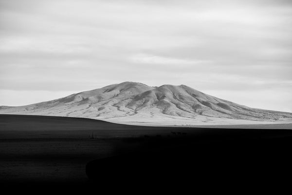 Black and white landscape photograph of New Mexico mountain catching the last rays of the setting sun, as the valley falls into deep shadow.