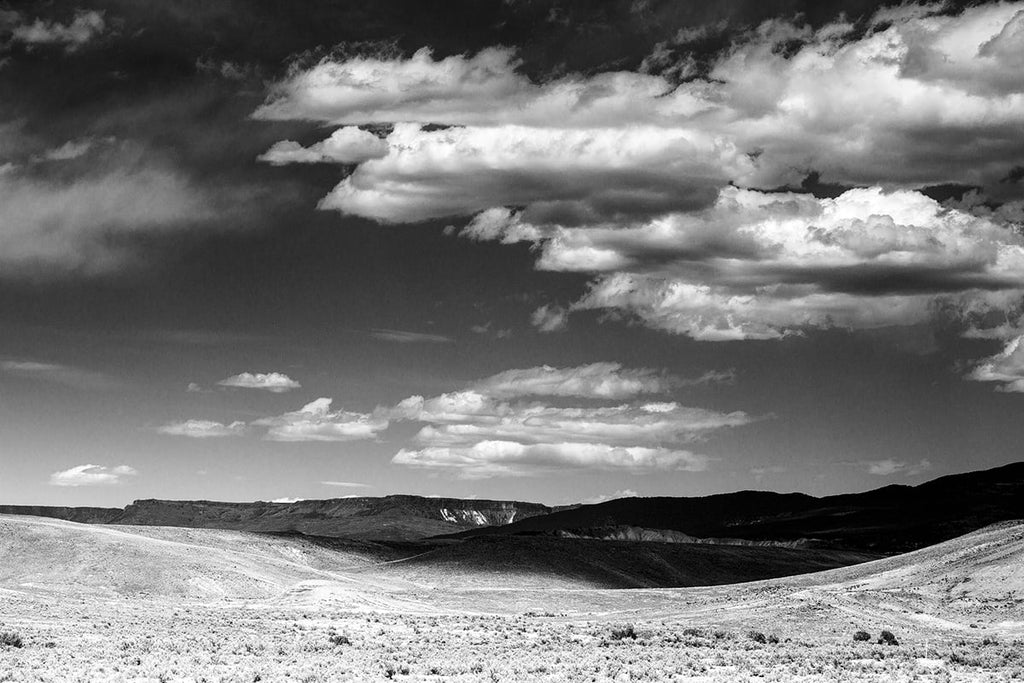 Black and white landscape photograph of Colorado foothills with cloud shadows.