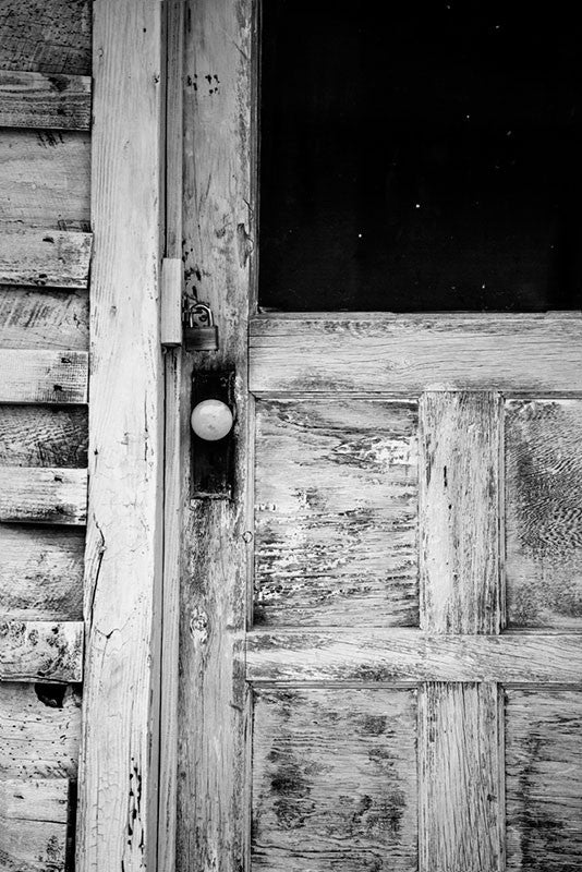 Black and white photograph of weathered and textured front door to the home of late blues musician Sleepy John Estes in Brownsville, Tennessee. 