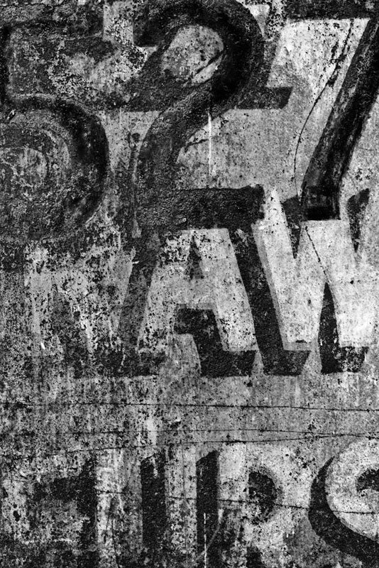 Black and white fine art photograph of the old painted "Raw Furs" signs on the building at 527 Conti Street in the French Quarter of New Orleans, Louisiana.