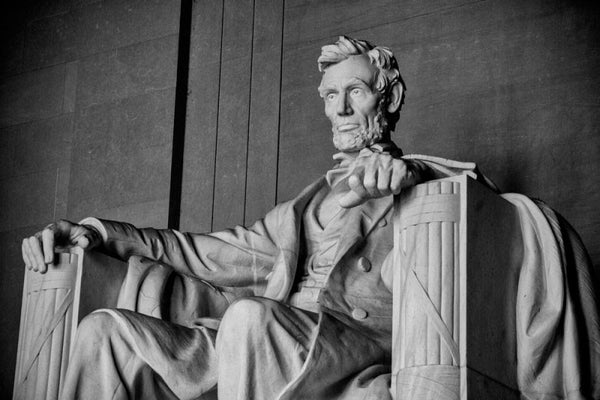 Black and white photograph of the huge statue of Abraham Lincoln at the Lincoln Memorial in Washington, D.C., seen from the right side in a three-quarter view.