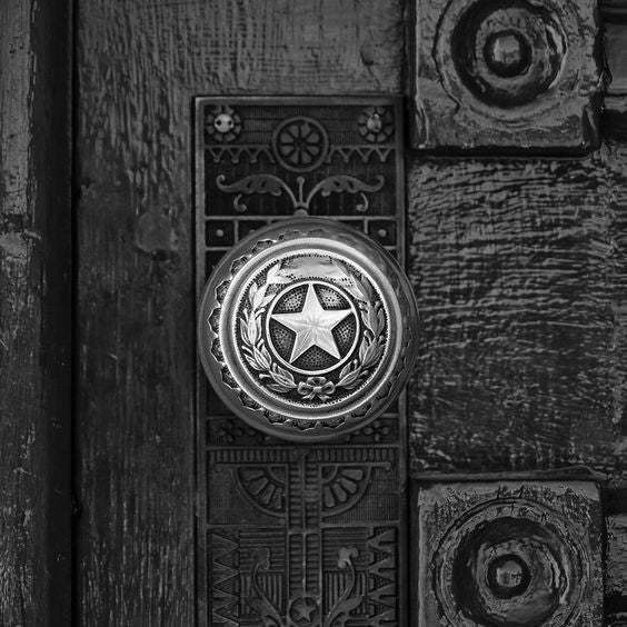Black and white photograph of a brass lone star door knob on a door leading into the Texas State Capitol Building in Austin. (Square format) This is one of the well-worn door knobs leading into the magnificent Texas state capitol building in Austin. Imagine how many interesting characters from Texas history must have touched this knob, and how many scoundrels!