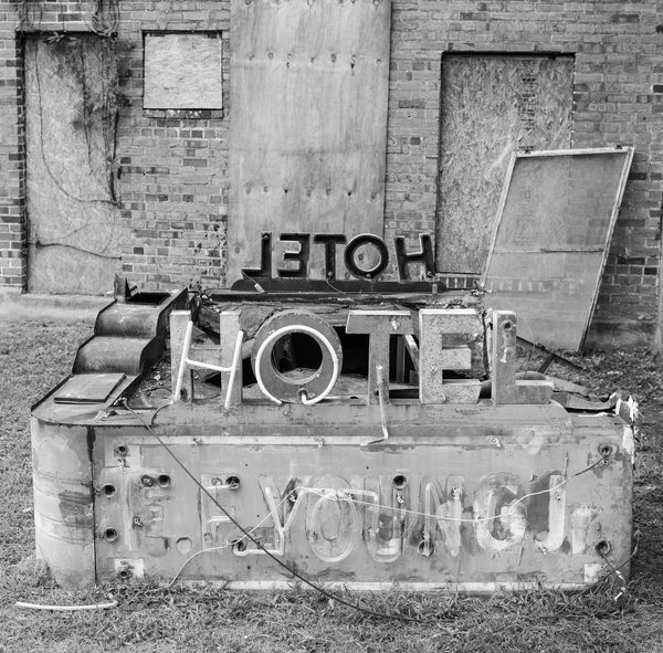 Black and white photograph of the old neon marquee sign from the historic E.F. Young Jr Hotel in Meridian, Mississippi. Built in 1946, the hotel was listed in the Green Book but later fell into ruins and was demolished in April 2023. Only the sign remains sitting in a vacant lot nearby.
