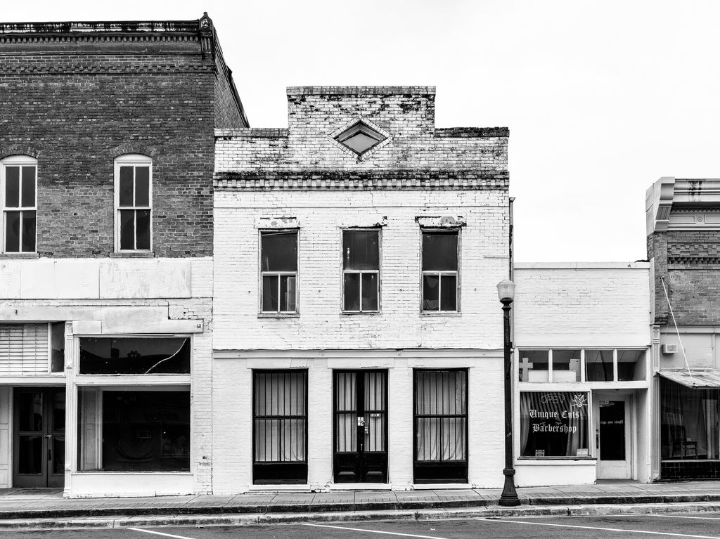 Black and white photograph of the historic H.H. Hooten Building in Greensboro, Alabama. Built in 1890, it served as a general store and later as a grocery store, and was photographed by Alabama native William Christenberry in 1961.