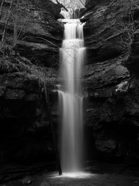 Black and white landscape photograph of a waterfall splashing into a small pool.