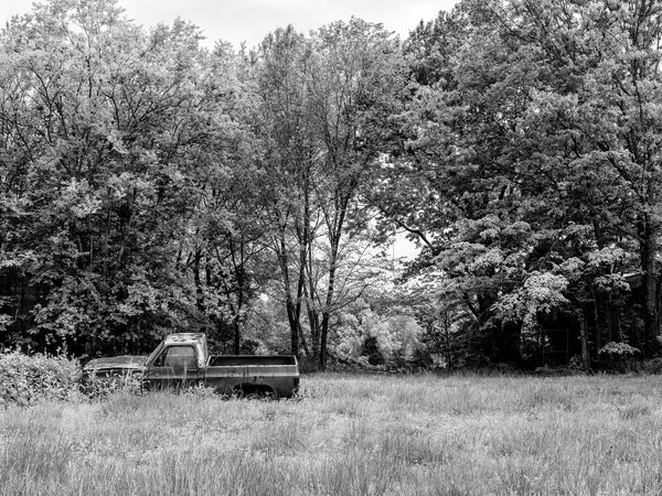 Black and white medium format photograph of an abandoned truck left in the tall grass of a field in Alabama in the American South.