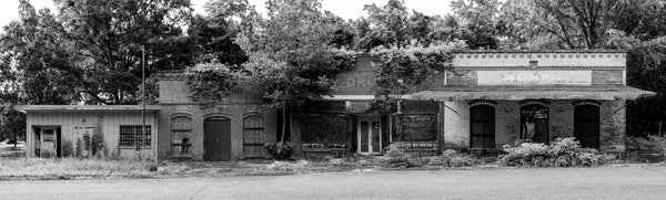 Black and white panoramic photograph of four buildings along an abandoned street in the small town of Seale, Alabama. From left to right, the buildings were a U.S. Post Office that was probably in operation from 1962 until the mid-90s; a hardware store, at least in the later years; City Drug Store, that once had a soda fountain inside; and last on the right was a feed and seed business called Starke’s Farm Supplies.