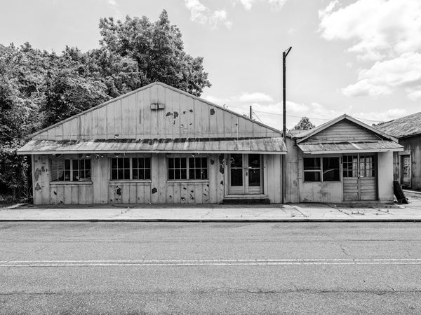 Black and white photograph of old abandoned storefronts in the American South.