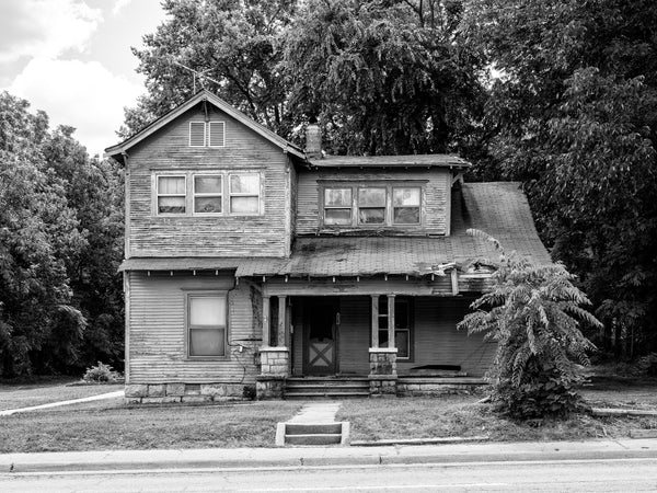 Black and white photograph of a beautiful abandoned two-story house found in a small town in Arkansas in the American South.