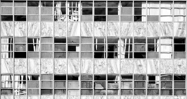 Black and white photograph of a large wall of broken windows along one side of the abandoned Freeman Hospital building in Joplin, Missouri, constructed in 1922 and closed in 1975.