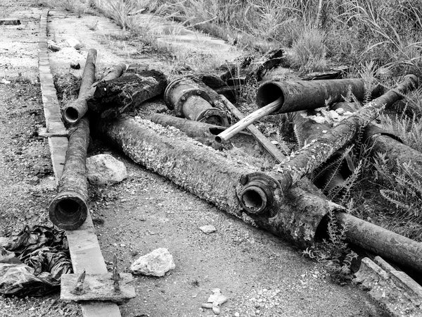 Black and white medium format photograph of old iron pipes and other debris on the pavement outside of Chattanooga's vast abandoned Wheland Foundry, which closed in 2003.