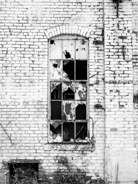 Black and white medium format photograph of a window with broken glass set into the the brick exterior of Chattanooga's vast, abandoned Wheland Foundry, which closed in 2003.