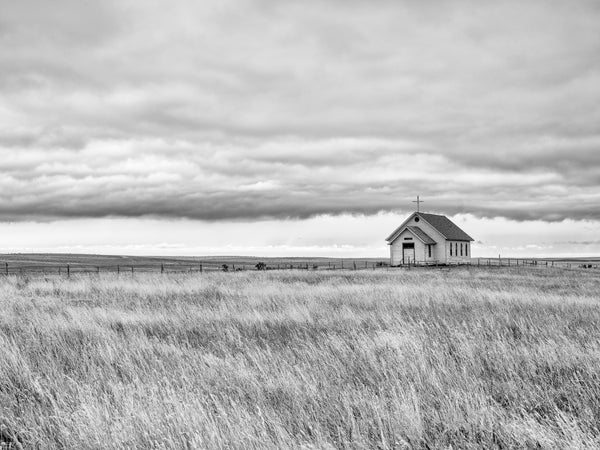 Black and white photograph of an isolated little church in the middle of the vast South Dakota prairie landscape.