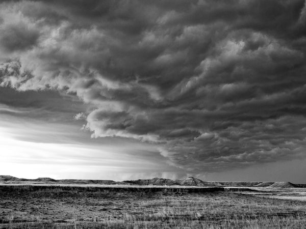 Black and white photograph of an intense storm front passing over the South Dakota Badlands.