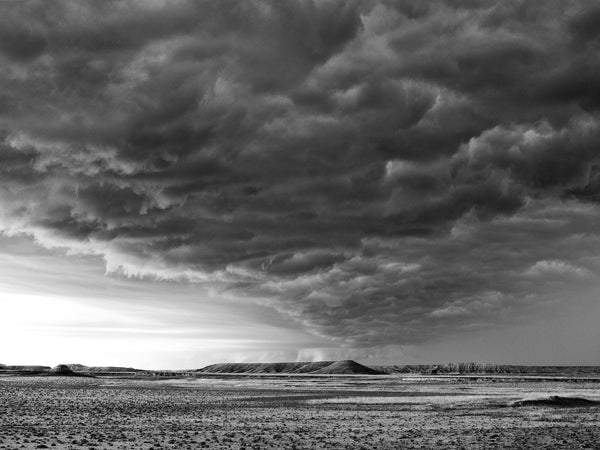 Black and white photograph of dark, boiling storm clouds over the vast landscape near the South Dakota Badlands.