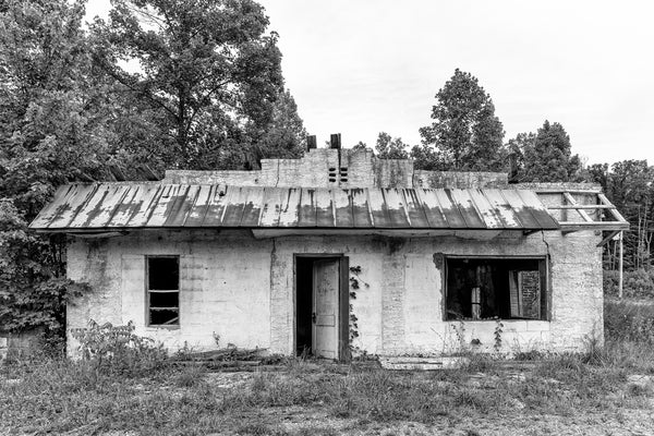 Black and white photograph of an abandoned whitewashed stone and block commercial building found in the Eastern mountains of the American South.