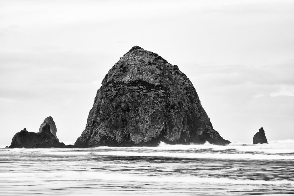 Black and white photograph of the iconic Haystack Rock at Cannon Beach, Oregon.