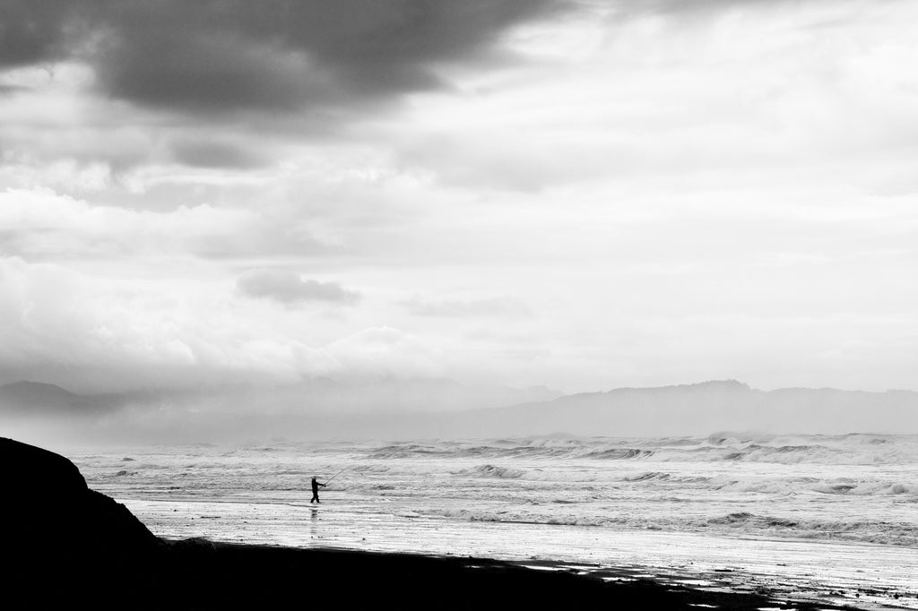 Black and white photograph of a courageous fisherman casting a line into the stormy surf along the Oregon coast.