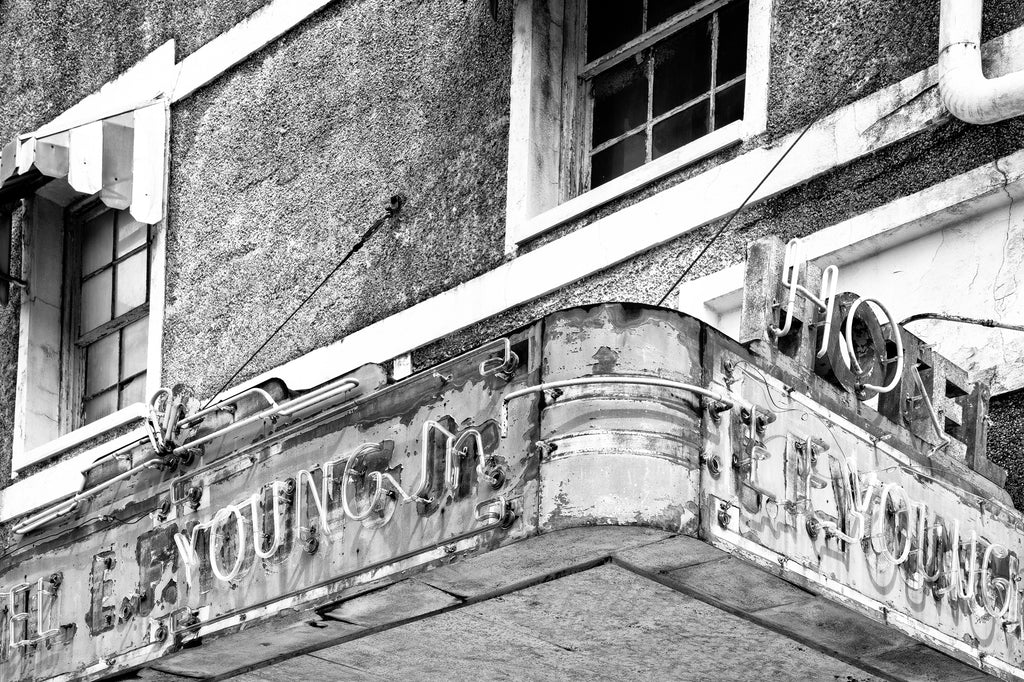 Black and white photograph of the old neon sign over the door of the abandoned E.F. Young Jr. Hotel in Meridian, Mississippi. Part of Meridian's historic Black business district, the E.F. Young Jr. Hotel was a Green Book listed hotel built in 1946. Long abandoned, it was demolished in April 2023.