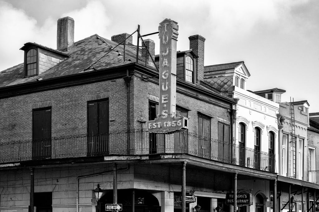 Black and white photograph of the vintage sign hanging over the balcony at Tujaque's Restaurant established 1856 in New Orleans.