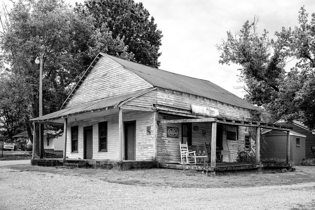 Black and white photograph of an old country store found along a backroad in the rural South. The hand-painted sign over the porch says "McBurry."