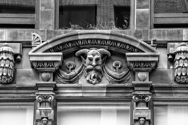 Black and white photograph of a mythological goat head man sculpted onto the exterior of a historic office building in downtown Pittsburgh.