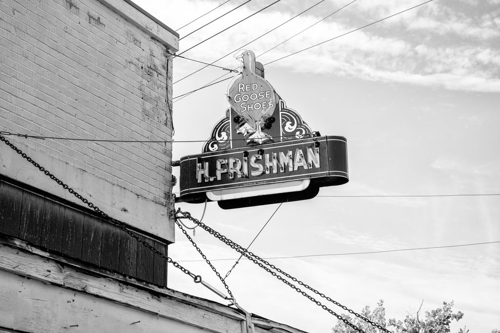 Black and white photograph of a vintage 1930s-era sign for the H. Frishman Dry Goods store in Port Gibson, Mississippi. The sign features the prominent logo of the Red Goose Shoes brand.