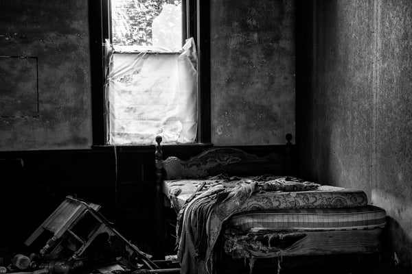 Black and white photograph of the tattered furniture inside a room previously used as a bedroom in one of the abandoned buildings at the ghost town of Union Level, Virginia.