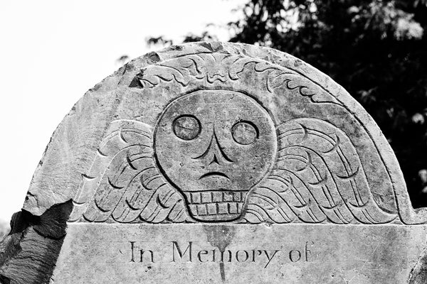 Black and white photograph of an iconic 1750s winged skull tombstone found in the historic Copp's Hill Burying Ground in Boston.