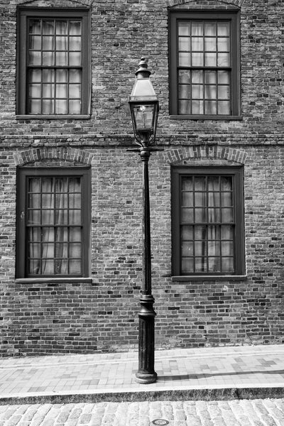 Black and white photograph of an old fashioned lamp post standing along a cobblestoned street in Boston's historic North End.