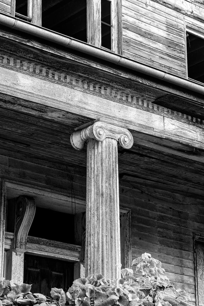 Black and white photograph of an Ionic-style wooden column on the front of the historic and abandoned Judge Mark Bird House, built circa 1840 in Woodstock, Virginia. The mansion also once housed the Woodstock Female Seminary.