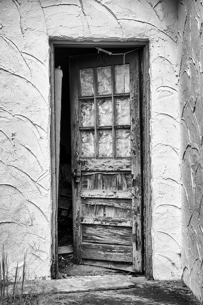 Black and white photograph of a weathered old door to one of the rooms of the historic Windsor Village Motel, which now stands abandoned in the small town of Pulaski, Tennessee.