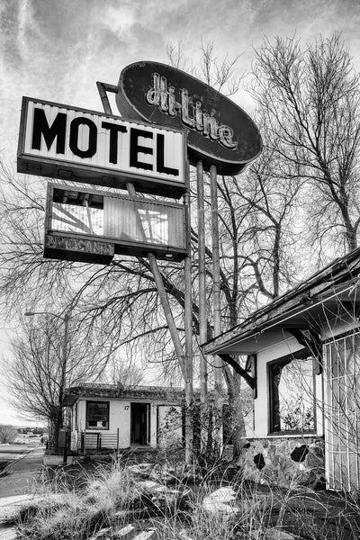 Black and white photograph of the vintage sign for the old Hi-Line Motel along Route 66 in Ash Fork, Arizona. Built in 1936 as the Hi-Line Modern Motor Court, each room had a covered parking space built in next to it - like a garage without a door. There was also a Shell station in the office with gas pumps in front. The modern sign we see now was installed in the late 1950s when the highway was widened and the fuel pumps were removed. That's when Route 66 was broken into divided lanes.