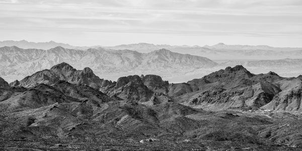 Black and white panoramic landscape photograph of layers of rugged mountain ridges in Arizona.